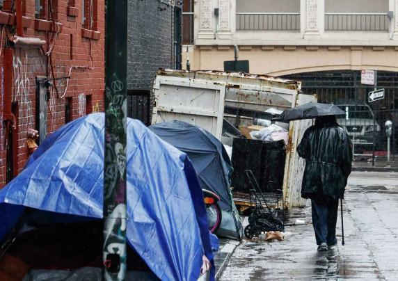 Person walking with umbrella near tents on sidewalk 