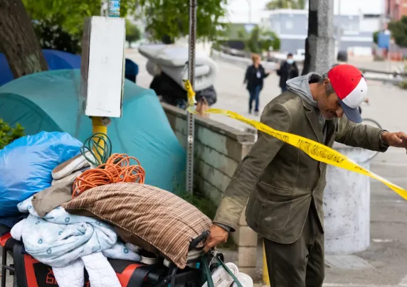 an unhoused individual moves their belongings