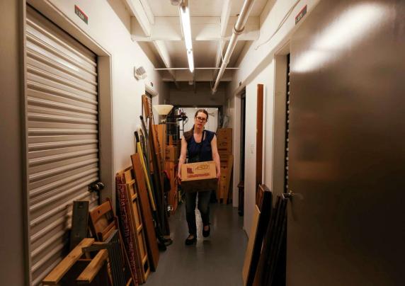 A woman removes a box from her storage unit, after watching the monthly rates jump to uncomfortable prices