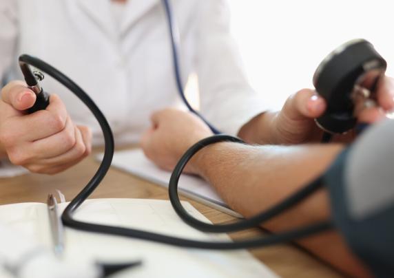 A person is taking someone's blood pressure using a blood pressure cuff.