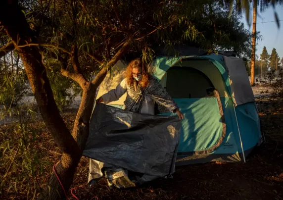 Woman folding a tarp outside a tent