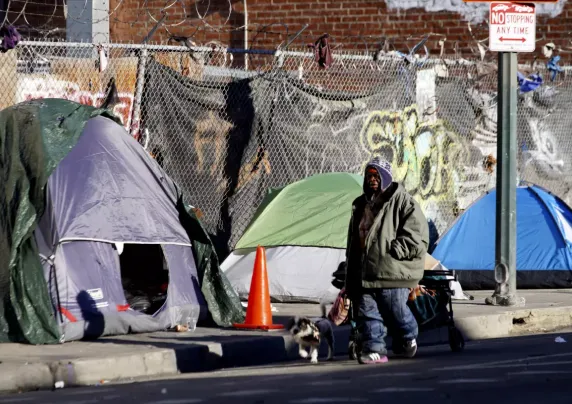 Man walks next to tents lining the sidewalk