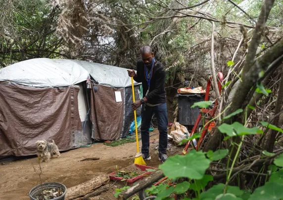 A man sweeps the ground outside a tent