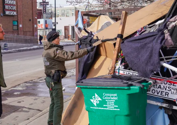A park ranger and healthcare worker approach encampment residence.