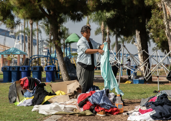 A person experiencing homelessness sorts through belongings in a park