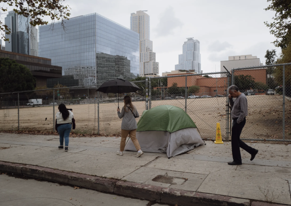 A tent on the sidewalk in front of the Los Angeles skyline