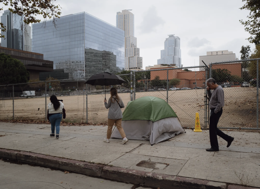 A tent on the sidewalk in front of the Los Angeles skyline