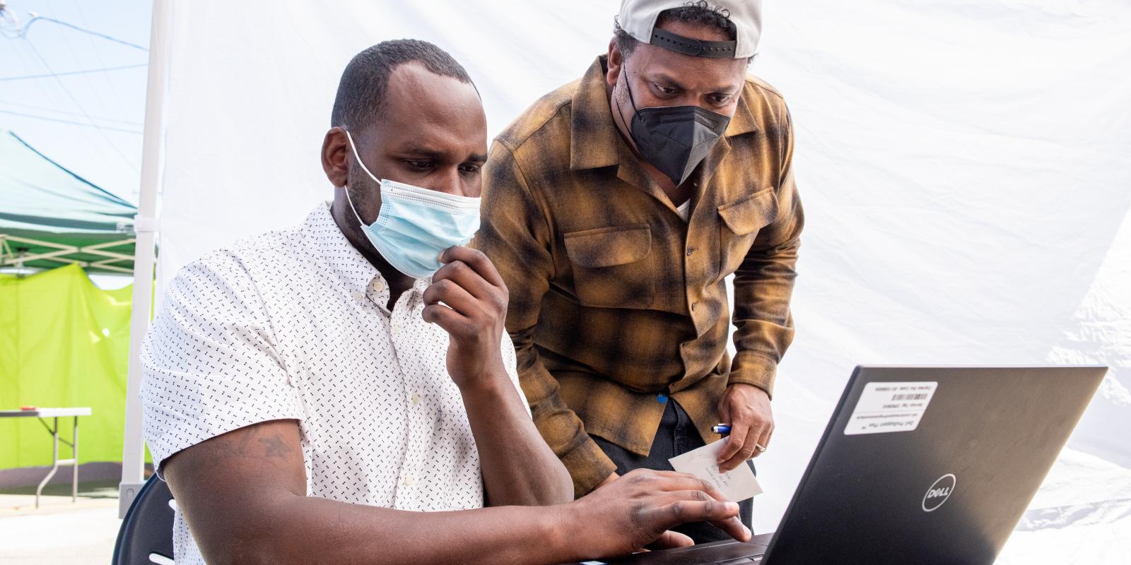 Two BHHI staff members looking at a laptop at the HOPE HOME study site