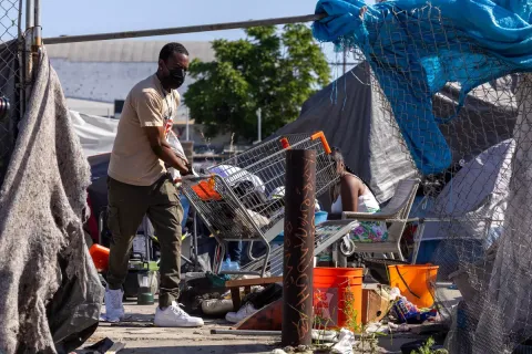 A man lifts a shopping cart outside tents